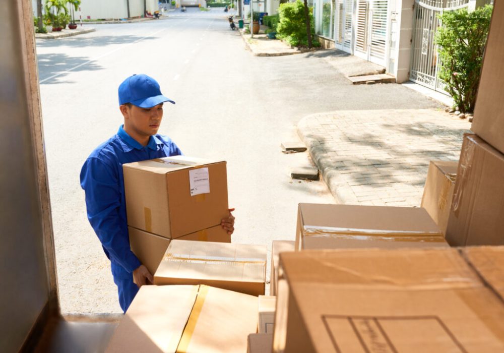 Young Vietnamese delivery man bringing boxes to his truck